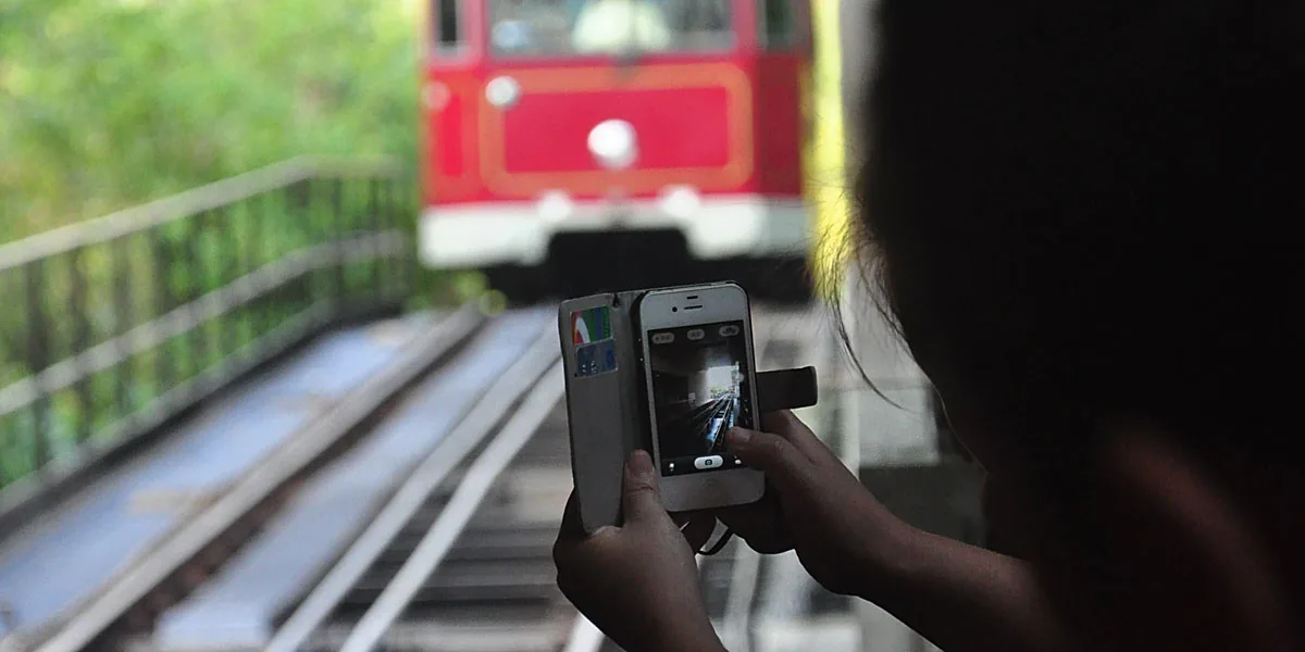 Tourists photographing the red Peak Tram climbing the steep track on Victoria Peak, Hong Kong